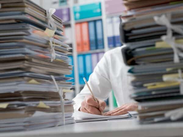 Business executive working in the office and piles of paperwork, he is overloaded with work